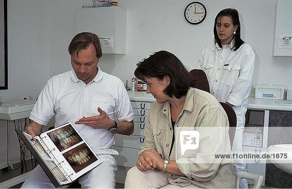 Dentist showing medical book to patient  Germany