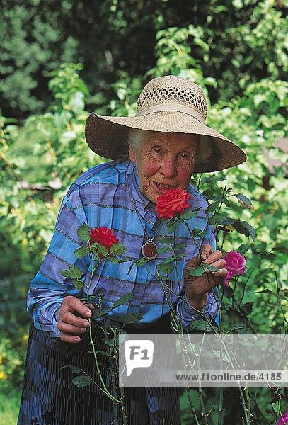 ältere Frau smelling Blume in einem Garten  Deutschland