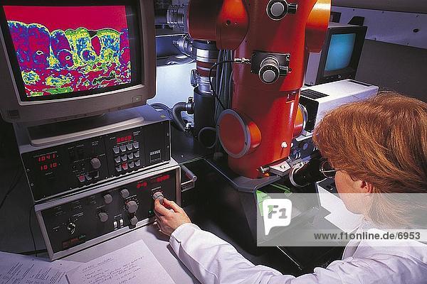 Frau arbeitet an Elektronen-Mikroskop im Labor