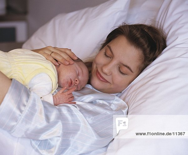 Nahaufnahme der junge Frau mit ihr neugeborenes Baby auf Bett
