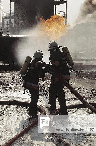 Rückansicht des zwei Feuerwehrleute Sprühen Wasser auf Schieneneinheit Niederlande