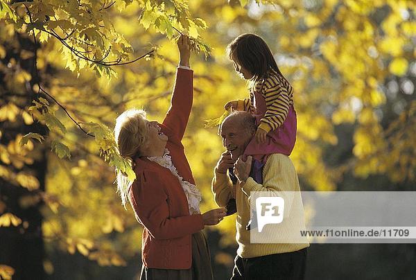 älteres Paar lächelnd mit ihren Enkel in einem park