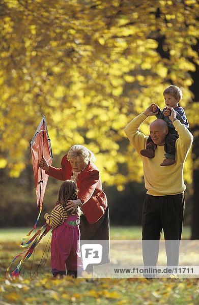 älteres Paar spielen mit ihren Enkelkindern in einem park