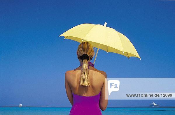 Rückansicht des Frau mit Sonnenschirm am Strand