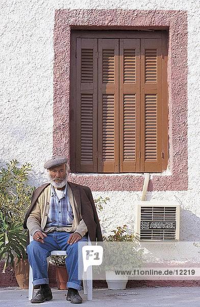 sitzend Senior Senioren Portrait Mann Wohnhaus frontal Griechenland Zakynthos