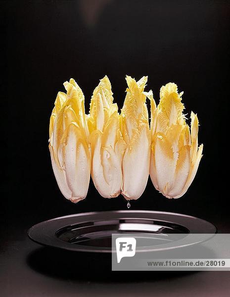 Close-up of fresh endives suspended over plate
