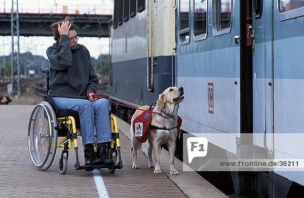 Frau sitzen im Rollstuhl mit Hund am Bahnsteig