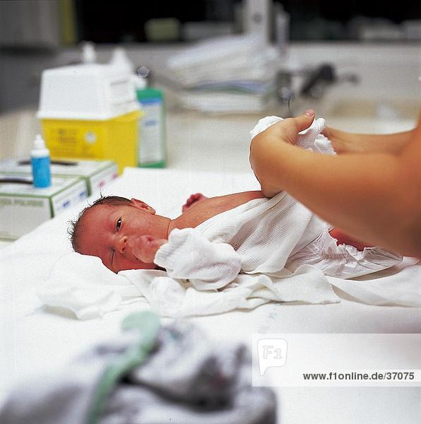 Krankenschwester Pflege für ein Neugeborenes Baby auf einem Krankenhausbett