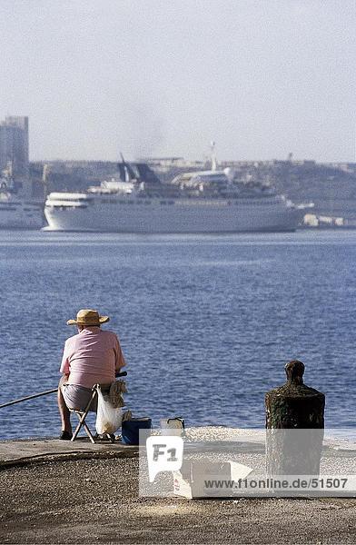 Rear view of fisherman at harbor  Valletta  Malta