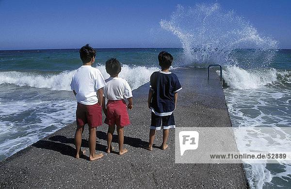 Kinder beobachten Wellen im Meer