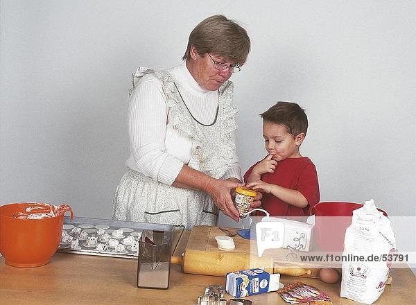 ältere Frau und ihr Enkel Cookies in Küche vorbereiten