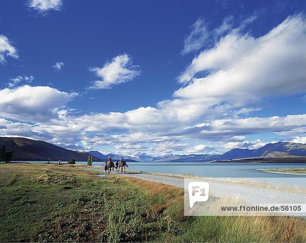 Two people riding horses at the coast Lake Tekapo South Island New Zealand