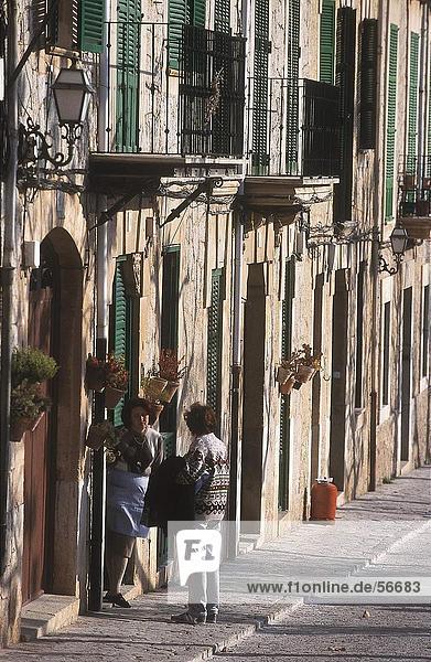 Two women talking in front of house  Valldemosa  Majorca  Balearic Islands  Spain