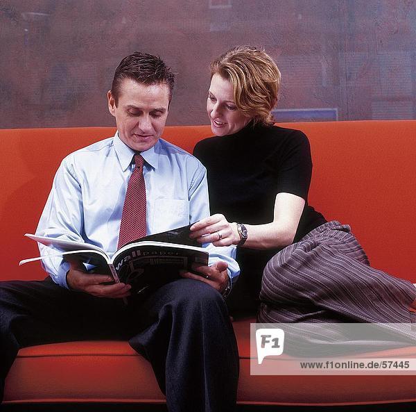 Kaufmann und geschäftsfrau lesen Magazin auf einer couch