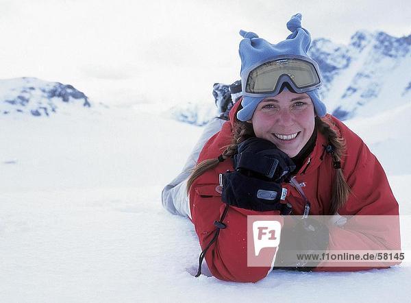 Portrait einer jungen Frau lächelnd in Skibekleidung auf Schnee