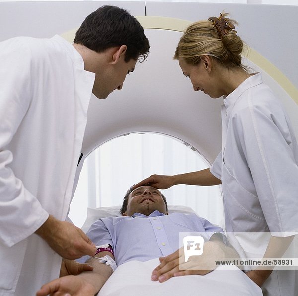 Two doctors examining patient on MRI scanbed