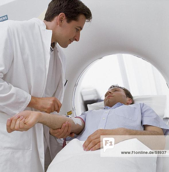 Male doctor giving injection to patient on MRI scanbed