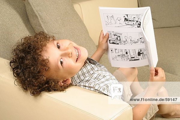 Bildnis eines Knaben hält ein Comic-Buch und lächelnd