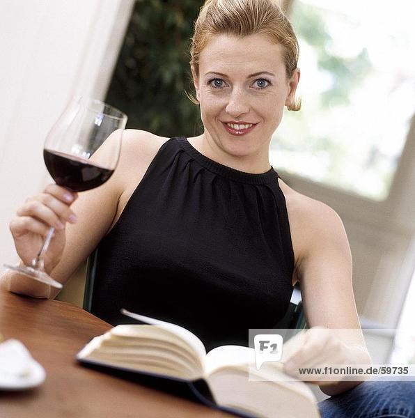 Portrait einer jungen Frau hält Glas Rotwein und lächelnd