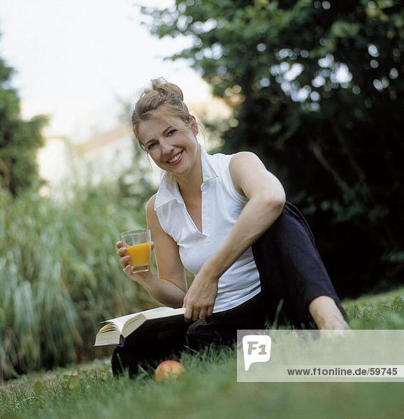 sitzend junge Frau junge Frauen Portrait Glas halten Garten Saft
