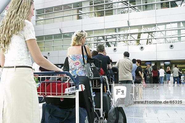 Menschen in Warteschlange mit Gepäck am Flughafen terminal