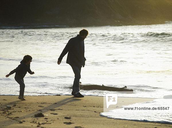 Man and his daughter walking on beach