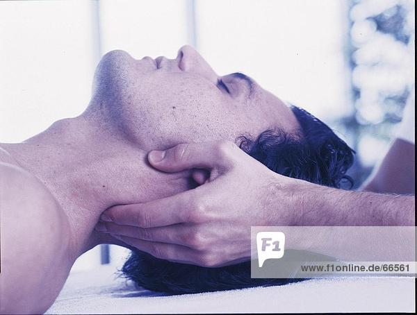 Des Physiotherapeuten Hände Massieren des Mannes Hals