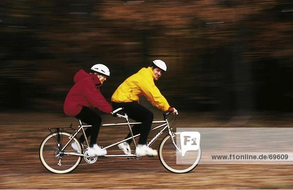 Side profile of couple riding tandem bicycle