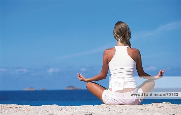 Junge Frau in Yoga Lage am Strand  Rückansicht