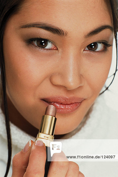 Young woman applying lipstick