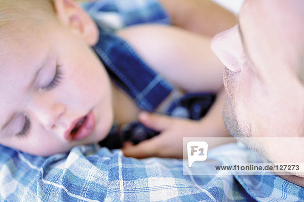 Baby schläft in den Armen des Vaters