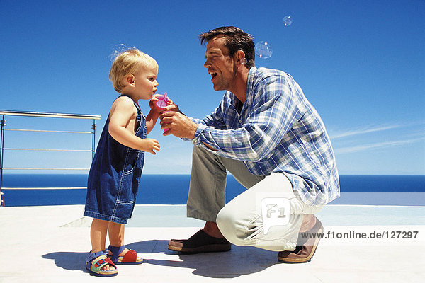 Father blowing soap bubbles with toddler