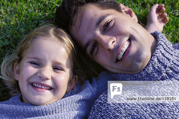 Vater und Tochter auf Gras liegend