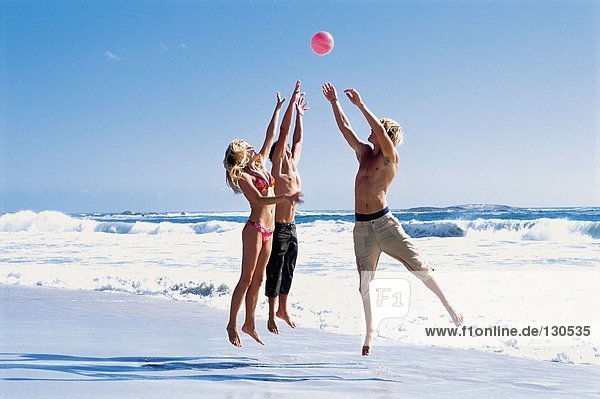 Gruppe von Freunden  die mit einem Ball am Strand spielen