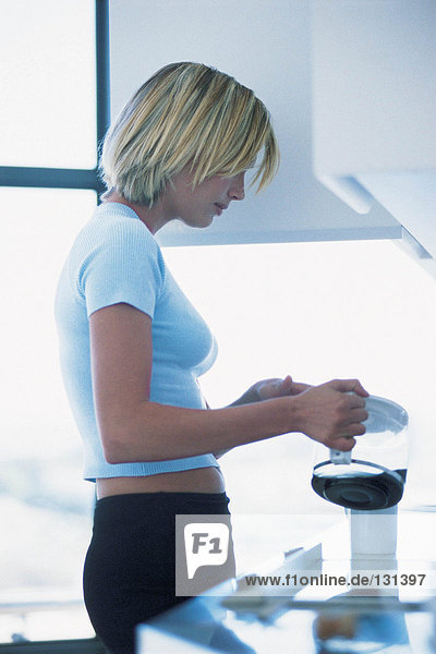 Büroangestellter gießt Kaffee in die Tasse