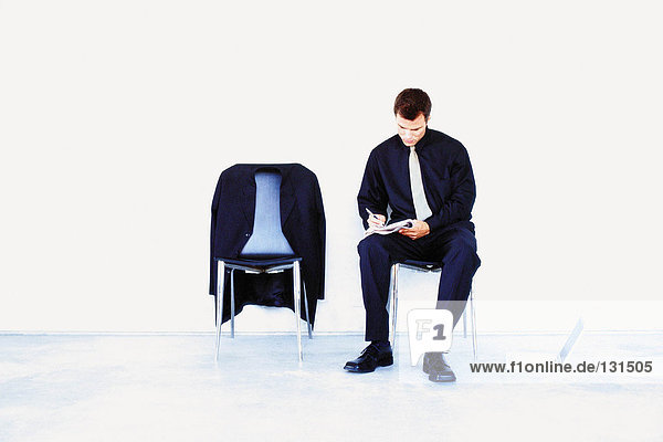 Man sitting on chair writing notes