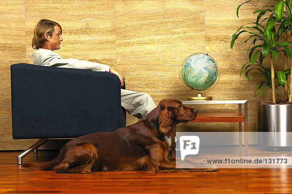 Geschäftsmann und sein Hund vor einem Globus
