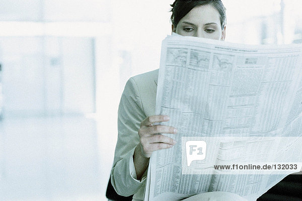 Geschäftsfrau beim Lesen einer Zeitung im Flughafenterminal
