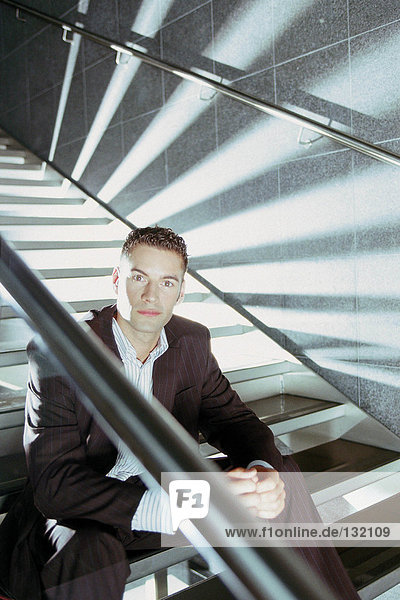 Geschäftsmann auf moderner Treppe sitzend