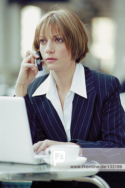 Businesswoman with laptop and cellphone at a cafe