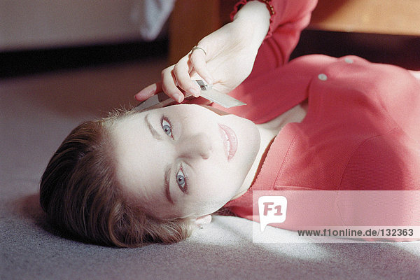 Woman lying on floor holding cell phone