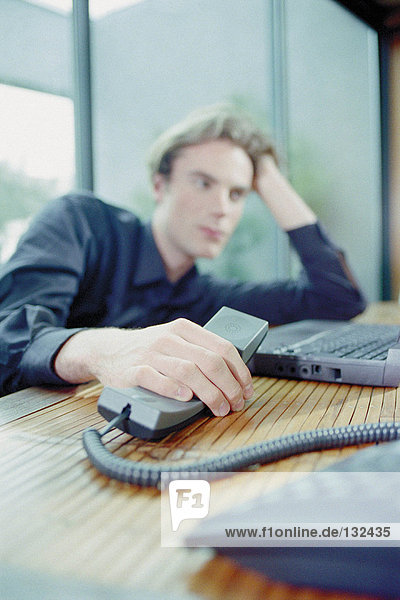 Man on laptop and telephone at home