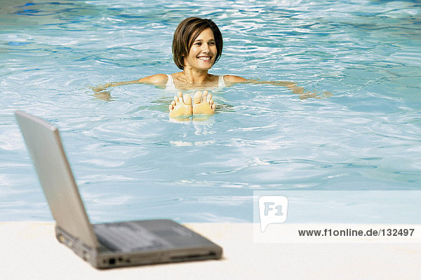 Frau im Schwimmbad mit Computer