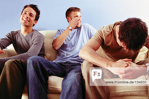 Männer scherzen auf dem Sofa.