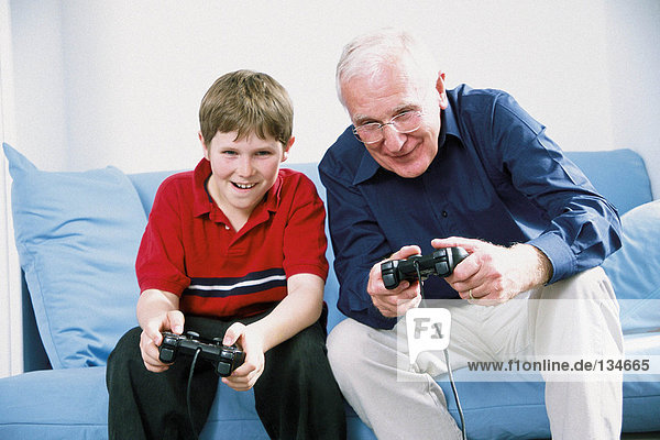 Großvater und Enkel spielen mit Computerspiel