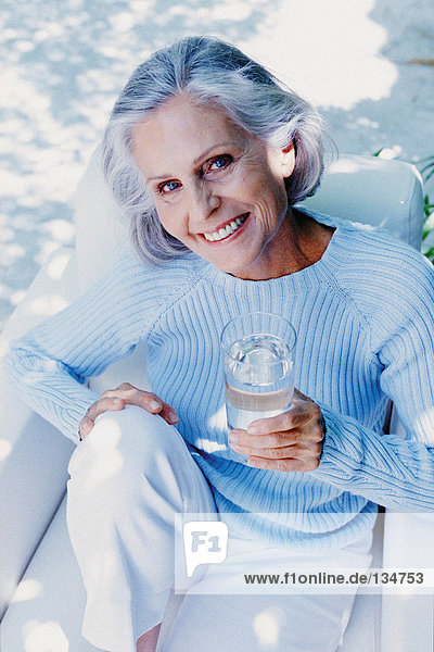 Alternde Frau  die im Freien trinkt