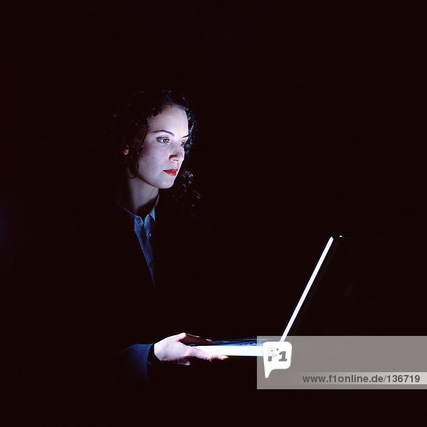 Geschäftsfrau mit Laptop im Dunkeln