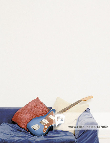 Eine E-Gitarre und ein blaues Samtsofa