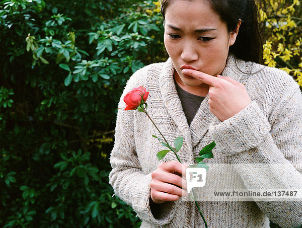 Mädchen verletzt ihren Finger an einem Rosendorn