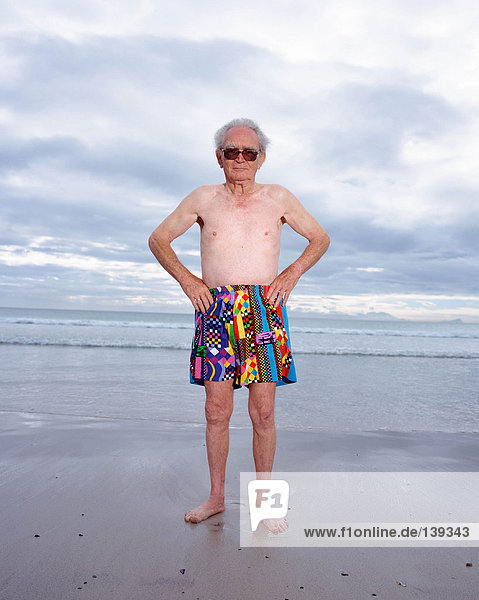 A mature man in bright shorts on the beach